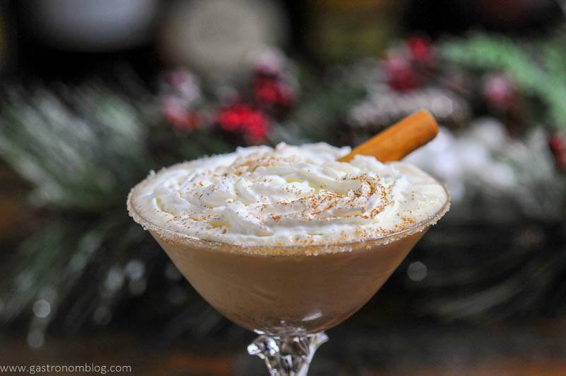 Tan cocktail in coupe with whipped cream and cinnamon stick