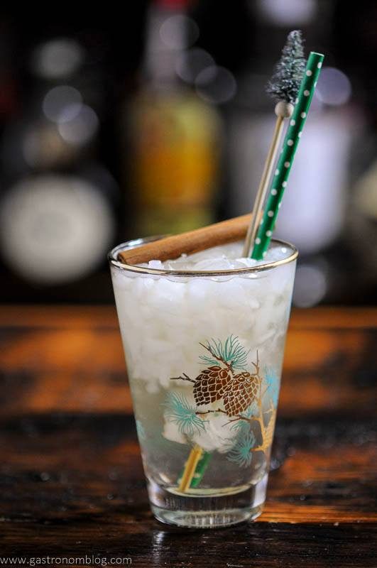 Cocktail in winter glass, cinnamon stick, green straw