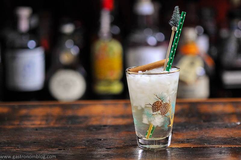 Cocktail in winter glass, pine stick, green and white straw, cinnamon stick