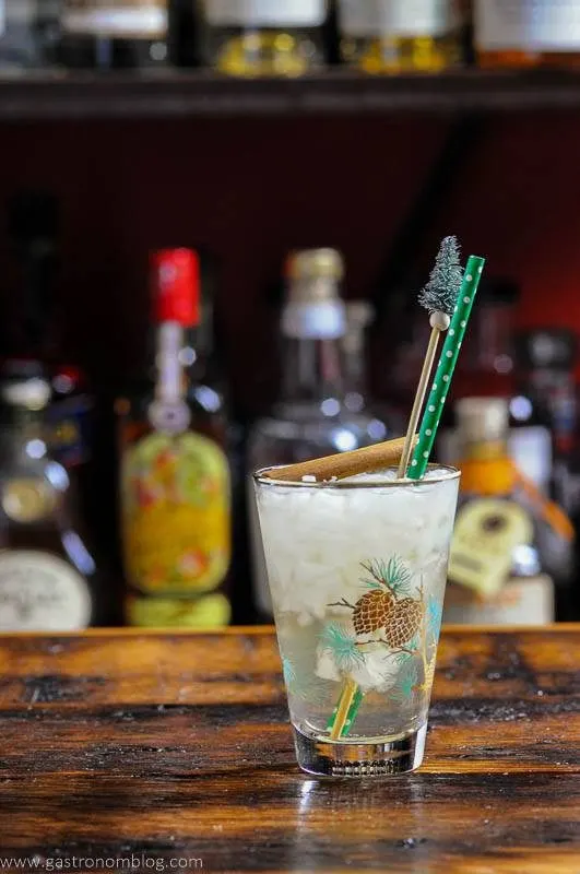 Gingerbread cocktail in winter glass, cinnamon stick, green and white straw