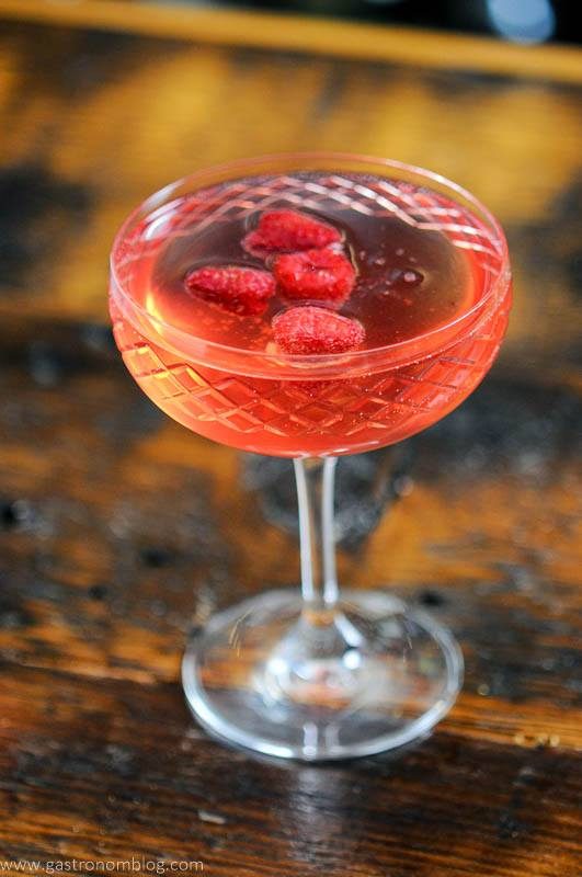 Pink gin champagne cocktail in coupe with raspberries