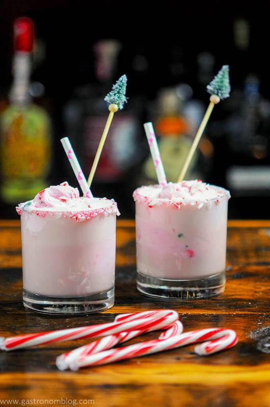 Pink Peppermint Eggnog Punch in rocks glasses, candy canes, straws and pine tree stirrers in glasses