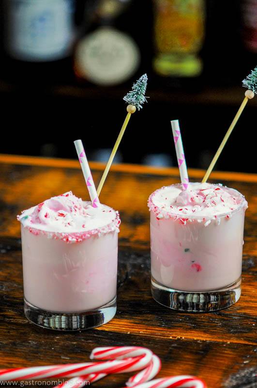 Pink peppermint eggnog punch in glasses with straws and candy canes