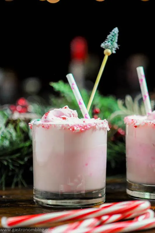 Pink Peppermint Eggnog Punch in rocks glasses, candy canes, straws and pine tree stirrers in glasses