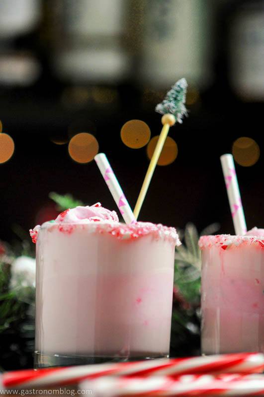 Pink Peppermint Eggnog Punch in rocks glasses, candy canes, straws and pine tree stirrers in glasses