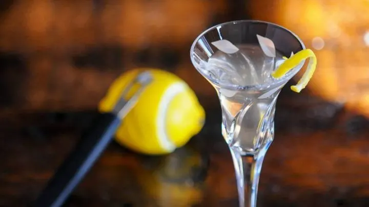 Cocktail in glass, lemon peel, lemon behind