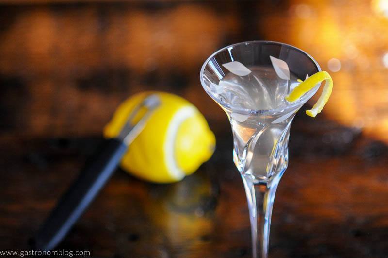 Cocktail in glass, lemon peel, lemon behind