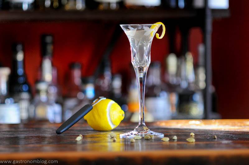 Aquavit cocktails in glass with lemon peel, lemon behind