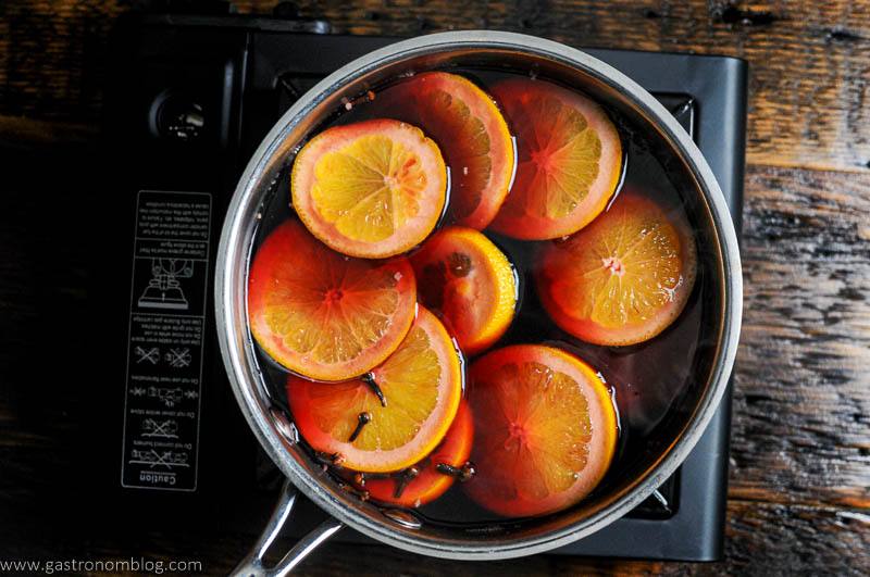 Citrus slices in wine in a saucepan on a burner