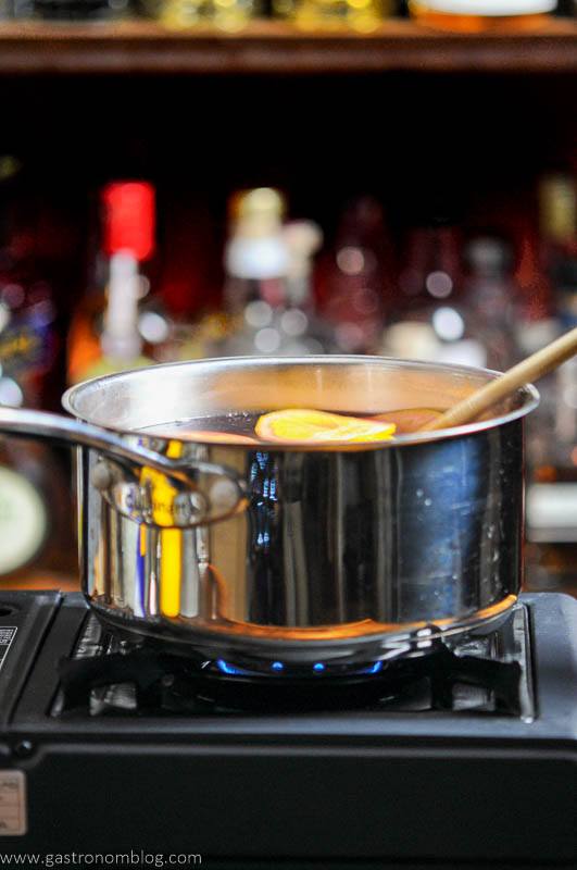 Citrus slices in wine in a saucepan on a burner