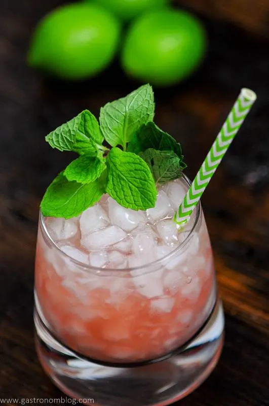 Pink cocktail in glass with green straw and mint