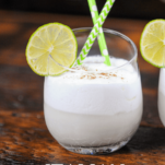 White drink in glass with lime wheels, green straw