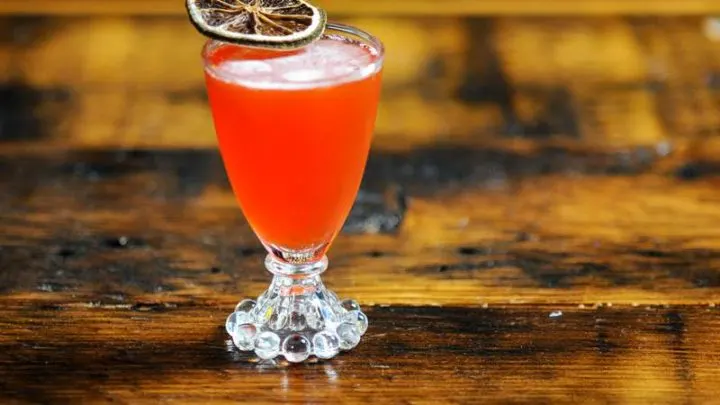 Pink cocktail in glass with citrus slice