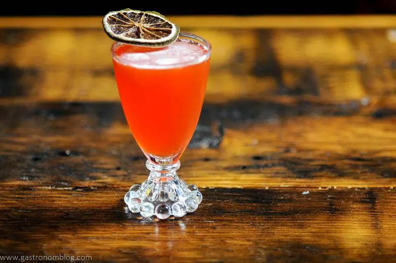 Pink cocktail in glass with citrus slice