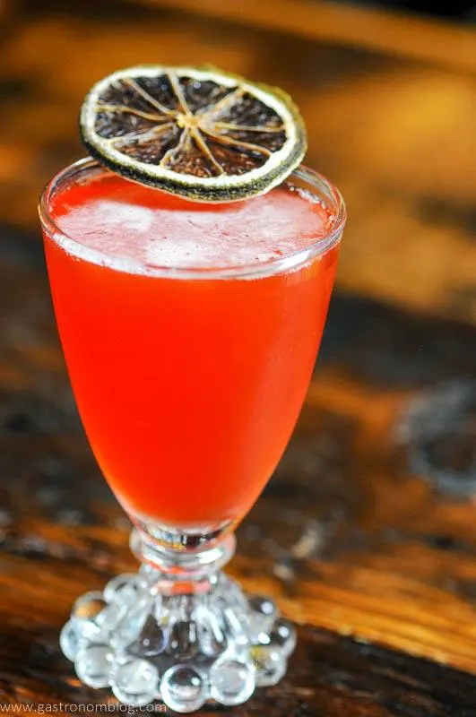 Pink cocktail in glass with citrus slice