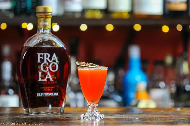 Cocktail in glass with liqueur bottle behind