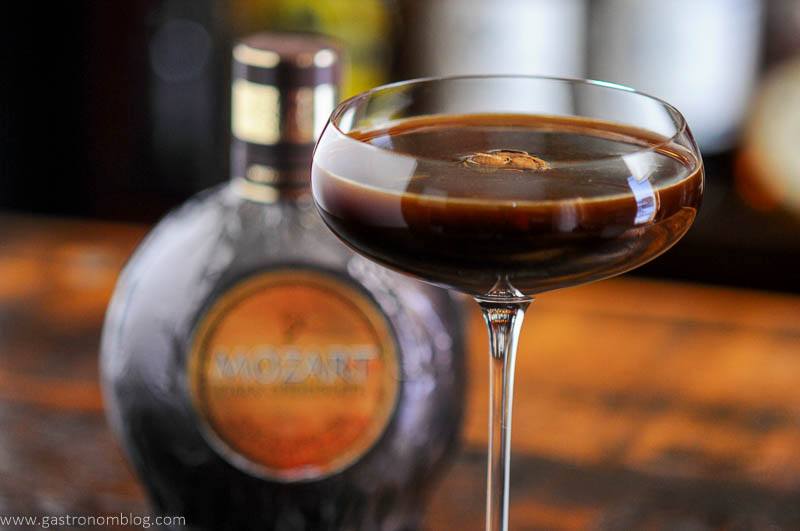 Brown cocktail in coupe, brown bottle behind