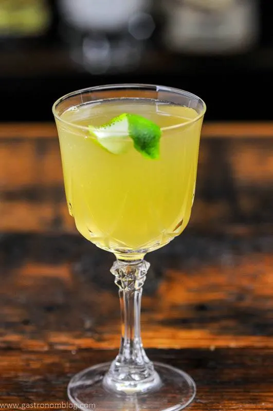 Yellow cocktail with lime peel