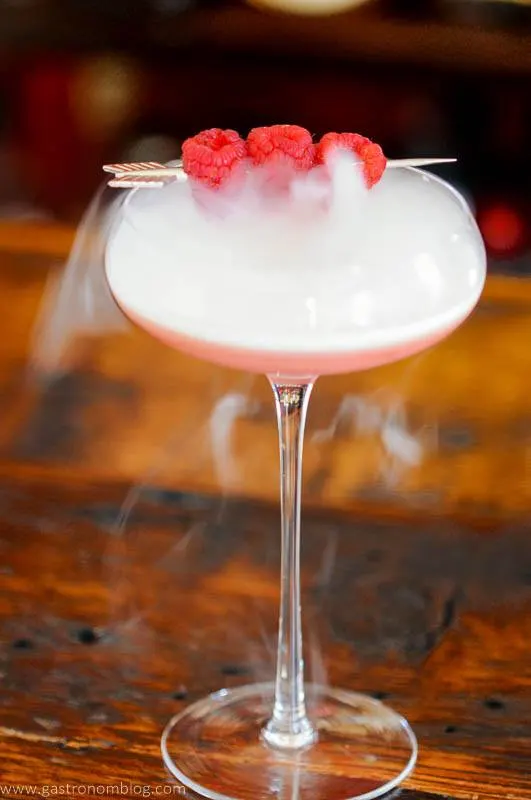 Pink cocktail in coupe with berries and dry ice