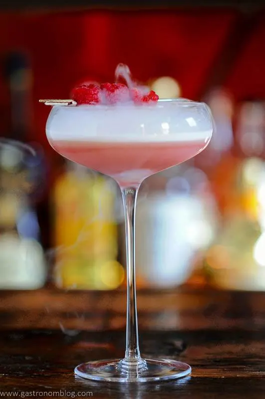 Pink cocktail in coupe with raspberries and dry ice