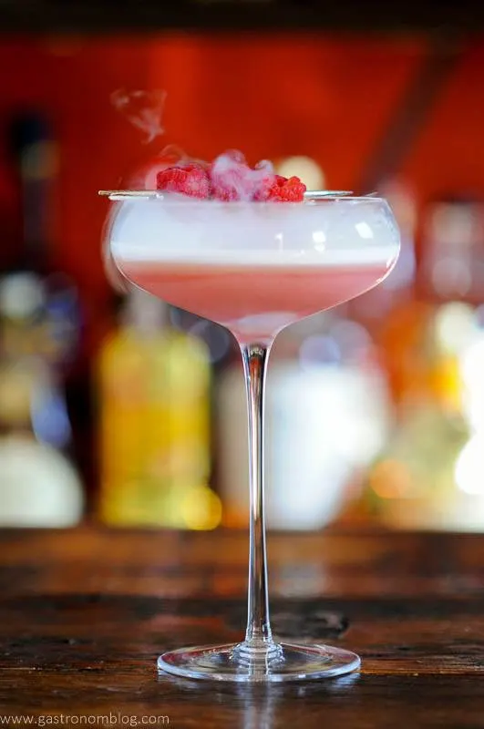 Pink cocktail in coupe with raspberries and dry ice