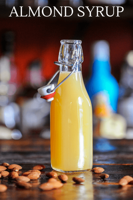 creamy yellow Orgeat Syrup recipe in bottle, almonds around