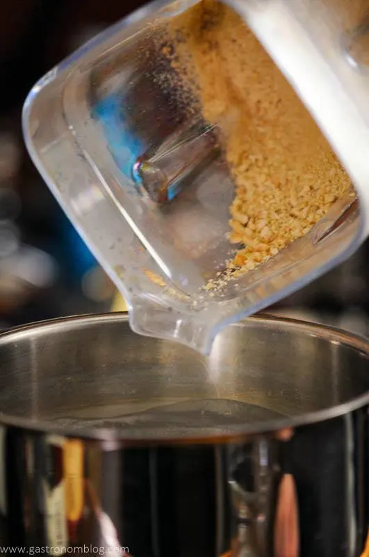 Crushed almonds being poured into saucepan