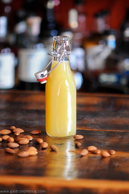 creamy yellow Orgeat Syrup in bottle with almonds