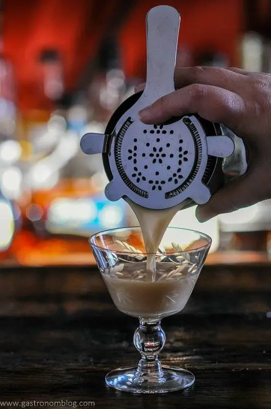 Cocktail being poured from shaker into glass