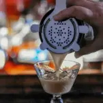 tan Cocktail being poured into glass from shaker