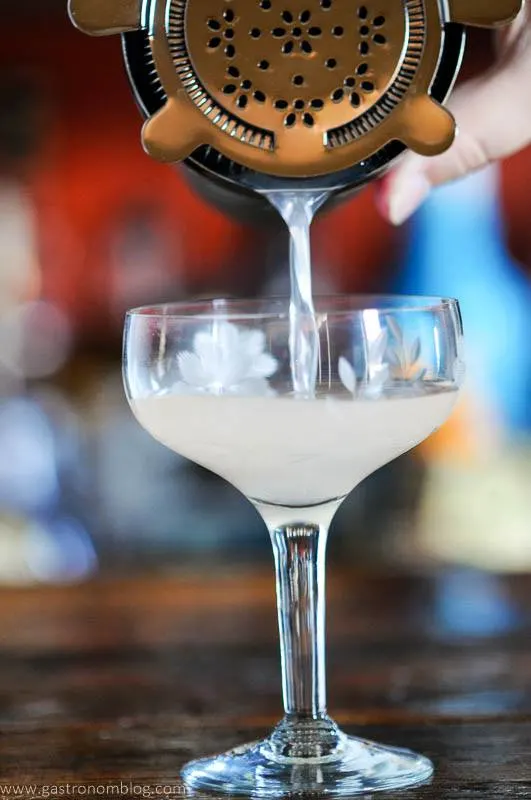 Rhubarb Gimlet Cocktail Recipe being poured into coupe from shaker