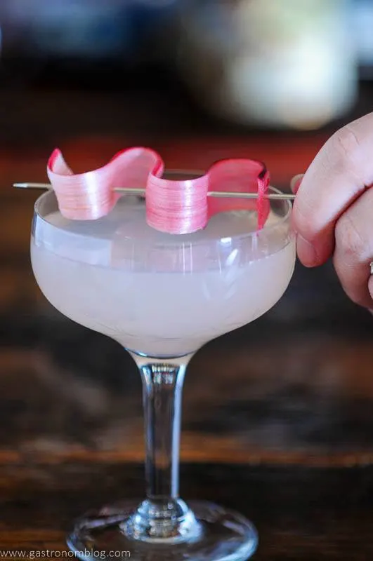 Pink cocktail in coupe with rhubarb strip garnish
