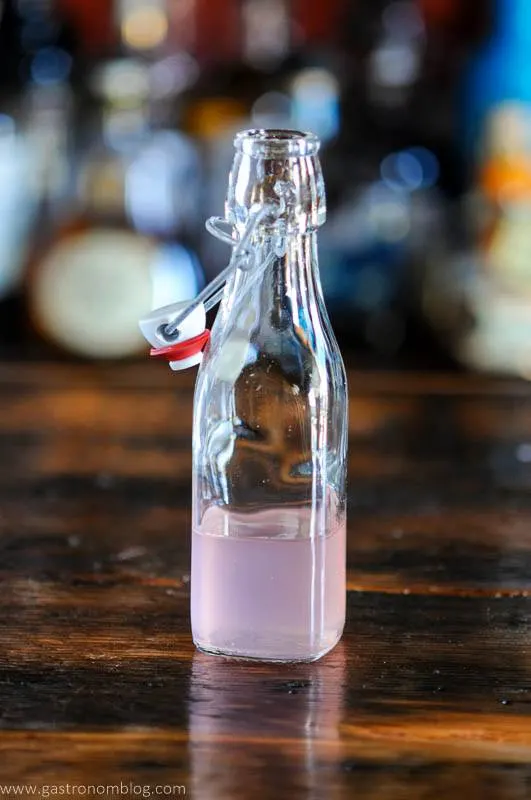 Pink Rhubarb Syrup in glass bottle with swingtop on wood table