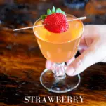 PInk cocktail in glass with strawberry, hand holding glass