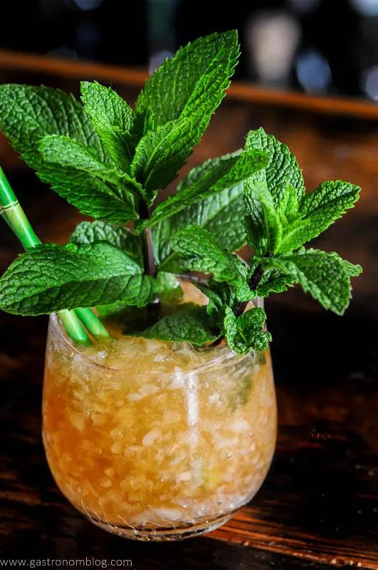 Tan Navy Grog cocktail in glass with crushed ice, mint bunches and green straws