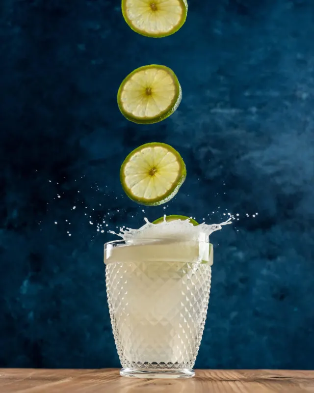 Limes being dropped in a margarita