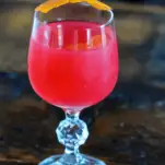 Bright pink cocktail in glass wtih orange peel