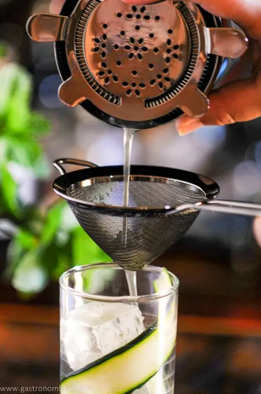 Cocktail being double strained from shaker into glass