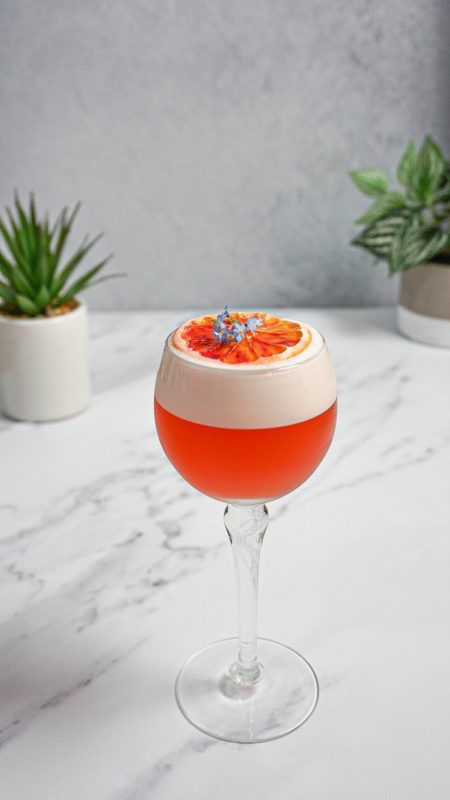 Orange cocktail with white foam on white background