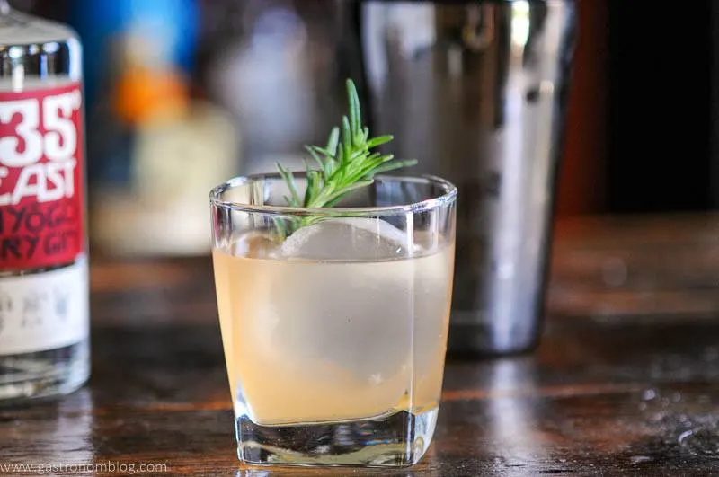 cocktail in glass with rosemary, shaker behind