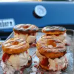 Glazed doughnut ice cream sandwiches on a cookie sheet outside