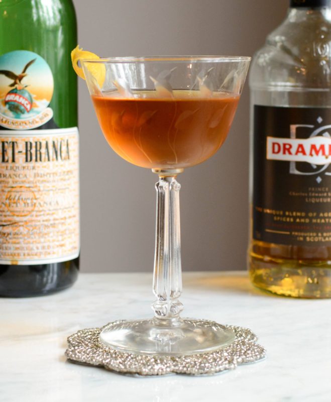 Brown cocktail in coupe, bottles behind