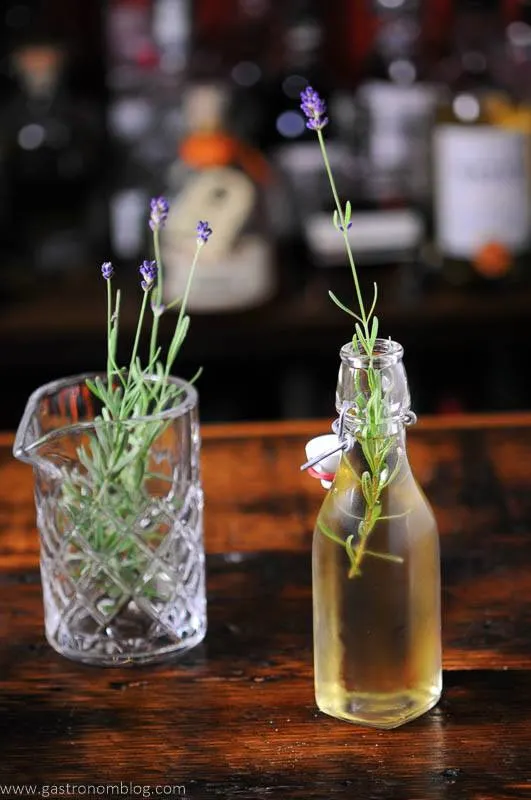 Lavender syrup in bottle, lavender sprigs in glass behind