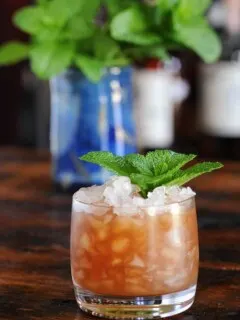Ancient Mariner cocktail, orange drink in rocks glass with crushed ice and mint sprig