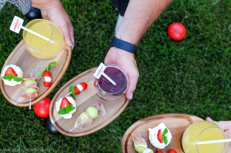 Appetizers and wine glasses on wooden trays held by hands