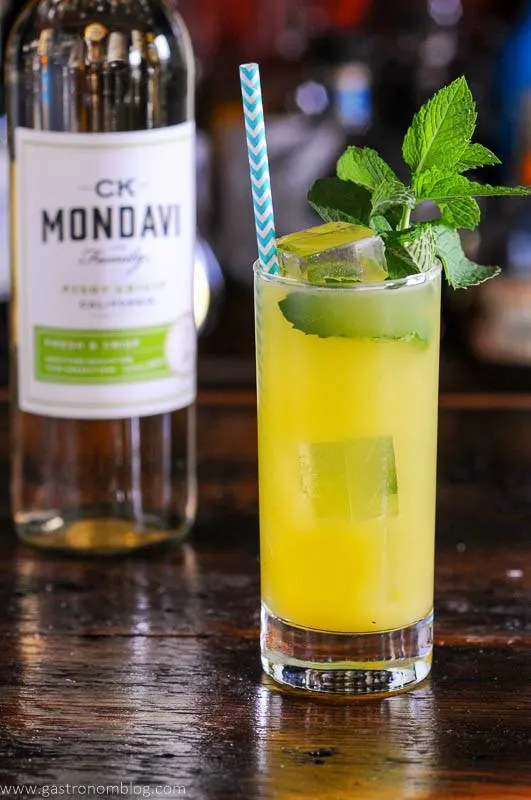 Orange wine cocktail recipes with mint and straw, wine bottle behind