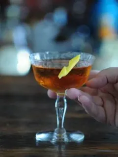 Brown cocktail in coupe with lemon peel