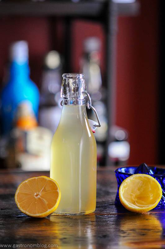 Yellow lemon simple syrup in bottle with lemons