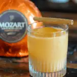 Orange cocktail in rocks glass, orange liqueur bottle behind
