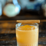 Orange pumpkin cocktail in rocks glass, cinnamon stick